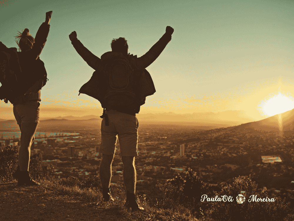 Casal hetero celebrando em frente ao pôr do sol- imagem: Canva