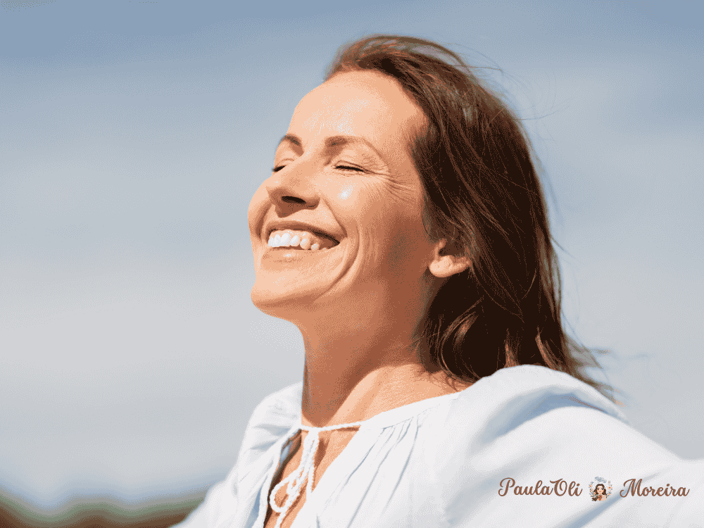 Mulher branca, se libertando aos ventos com o cabelo voando expressando um sorriso no rosto-Imagem:Canva
