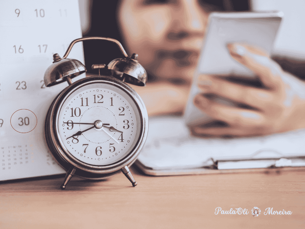 Mulher entretida com o celular, em vez de cumprir com suas devidas obrigaçoes- calendário e relógio- Autosabotagem- imagem: Canva
